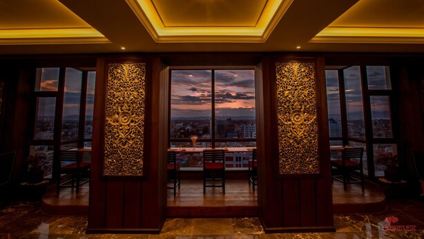 Amplia habitación con un ventanal grande que ofrece vistas a la ciudad, un candelabro y un panel decorativo en la pared.