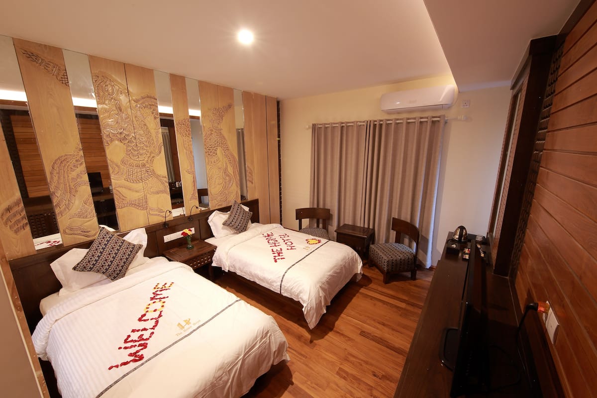 A hotel room with two beds, a desk, a chair, and a large mirror with wood paneling and artwork.