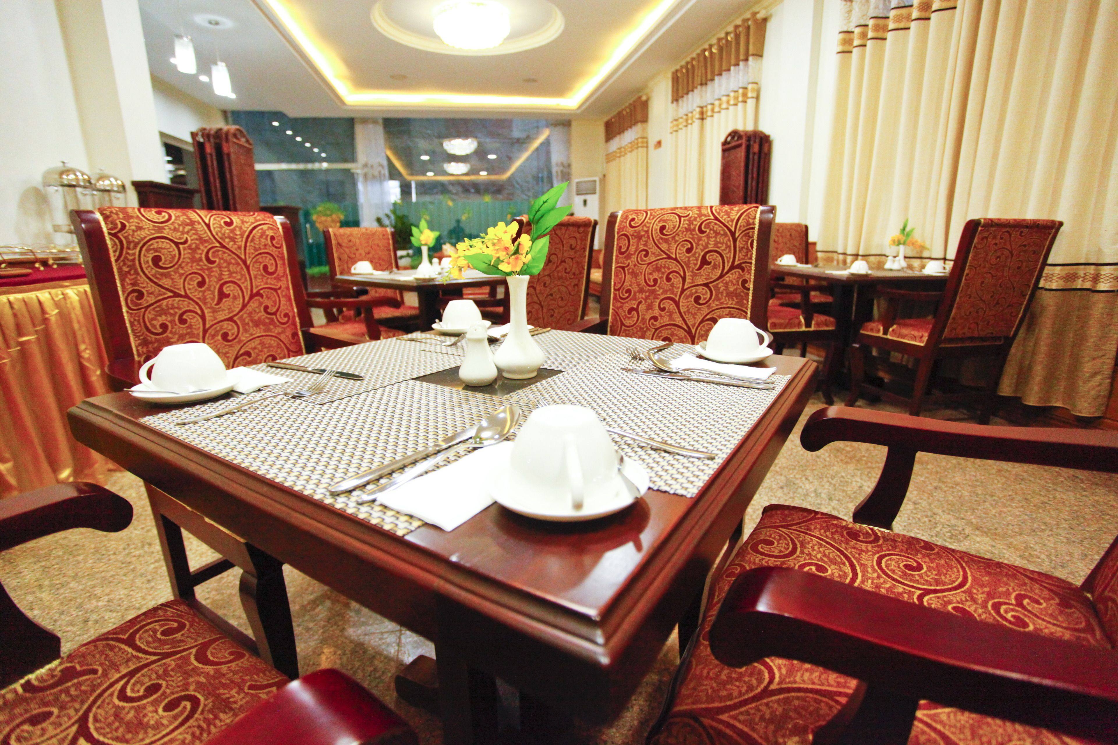 Uma sala de jantar com uma mesa de madeira posta para seis pessoas, rodeada por cadeiras estampadas.