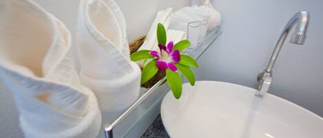 A bathroom with a white sink, a mirror, and a pair of white slippers.