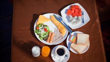 A table with a meal consisting of toast, salad, hot dogs, and a plate with carrots and a fork. There are also two cups, one with orange juice and one with coffee.