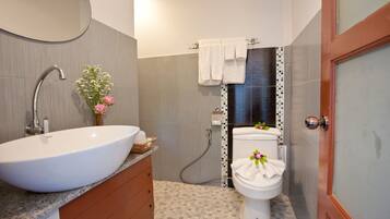 A bathroom with a white sink, a toilet, and a shower area.