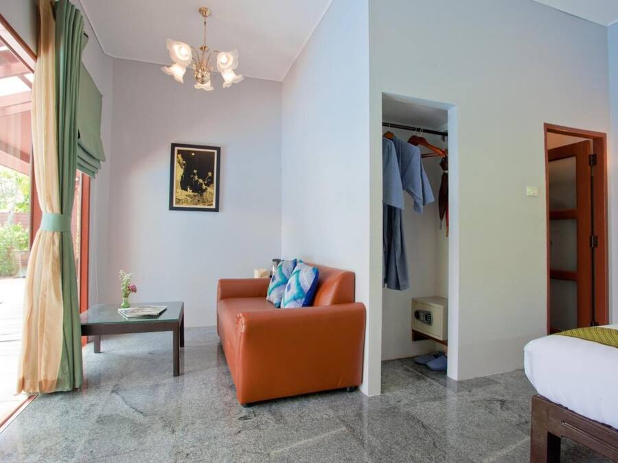 Ein Hotelzimmer mit Bett, Sofa, Tisch, Kleiderschrank und einer Chandelierleuchtre.