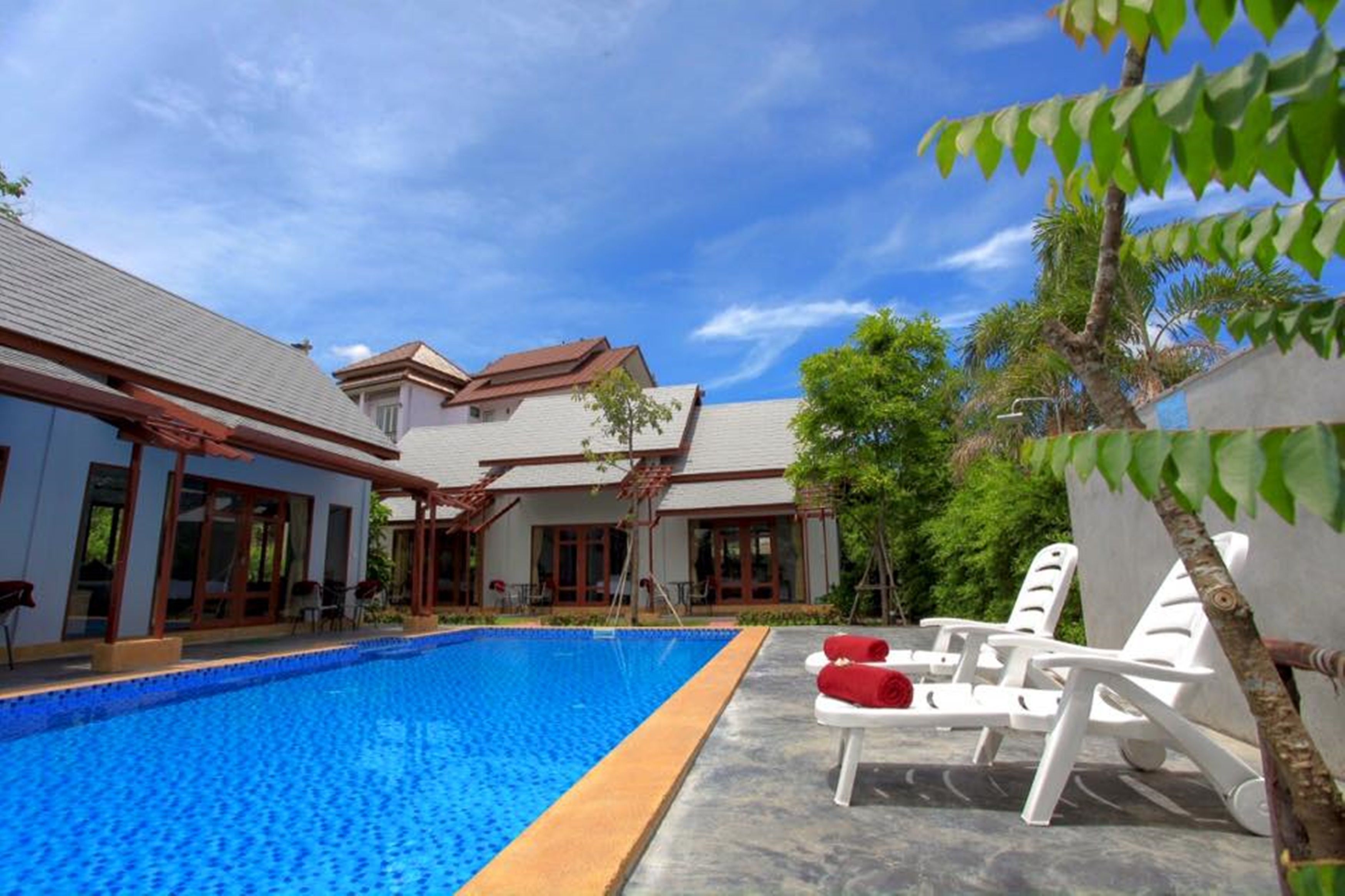 A swimming pool with lounge chairs and a covered patio area.