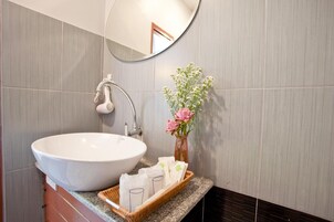 Un baño con un lavamanos grande blanco, un espejo y un florero con flores.
