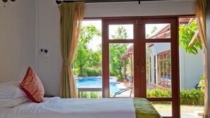 Un dormitorio con cama, vistas a una piscina exterior y una puerta que da a un área exterior cubierta.