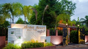 Señal de Ardea Resort Pool-Villa con entrada de ladrillo y abundante vegetación.