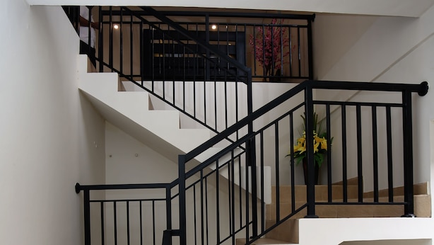 Un escalier à plusieurs niveaux, doté de rampes noires et de revêtements de sol en carrelage beige.