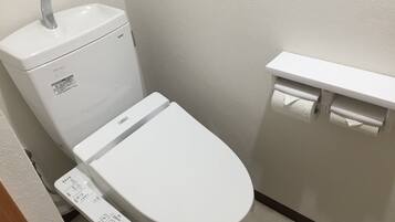 A modern toilet with a control panel, a wall-mounted sink, and a toilet paper holder.