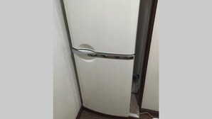 Un refrigerador blanco en un rincón de la habitación.