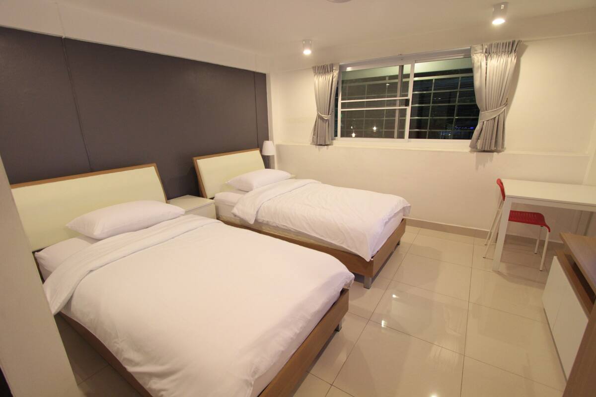 Une chambre d’hôtel avec deux lits, un bureau et une chaise.
