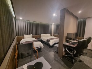 A hotel room with two beds, a desk with a computer, a chair, and a TV. - Yeow-B (Jinju)