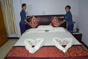 A neatly made bed with heart-shaped towels and decorative pillows. - Hotel Oriana (Yangon)