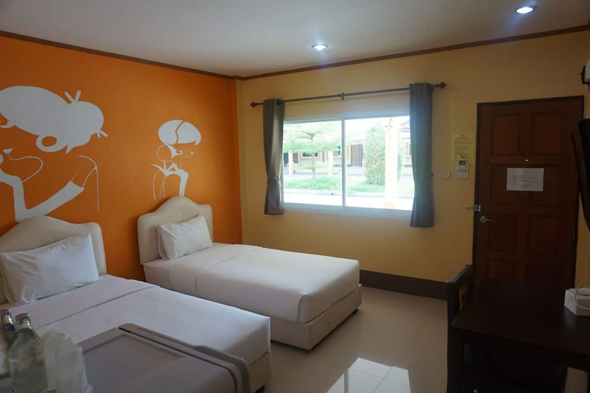 Une chambre d’hôtel avec deux lits, une fenêtre avec des rideaux, une porte en bois et une petite table.
