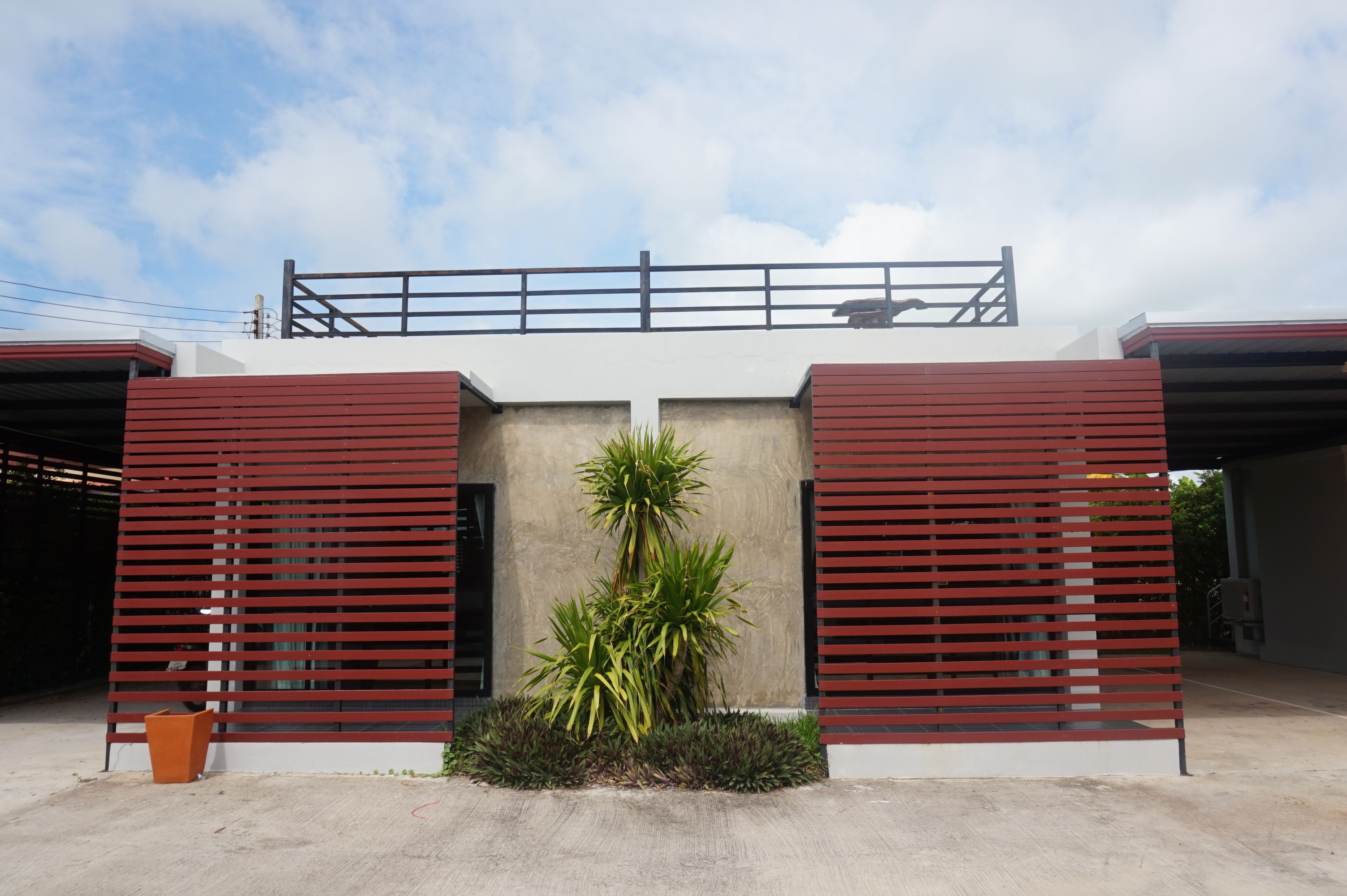 A modern building with a flat roof, a balcony, and a central plant.