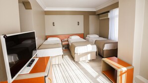 Et hotelværelse med to senge, et skrivebord med fjernsyn og et lille bord.