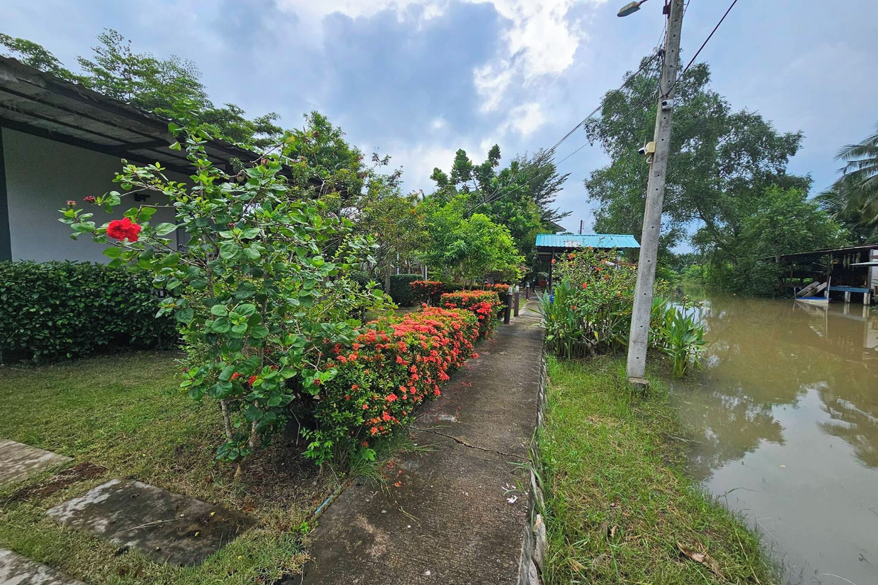 Un sendero inundado con un edificio a la izquierda y una estructura de techo azul al fondo.
