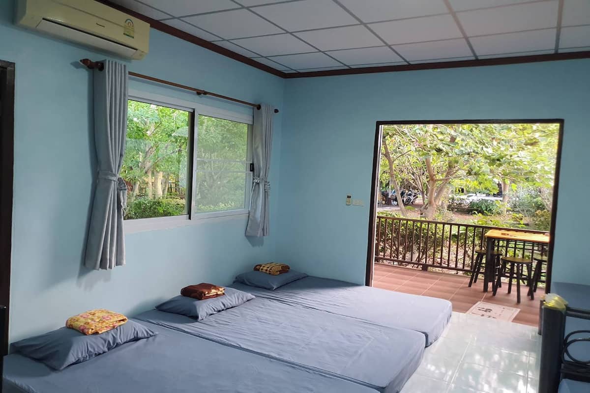 Een kamer met twee bedden, een raam en een balkon met een tafel en stoelen.