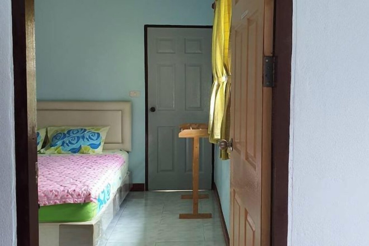 Ein Schlafzimmer mit einem Bett, einer Tür und einem kleinen Tisch mit gelber Tischdecke.