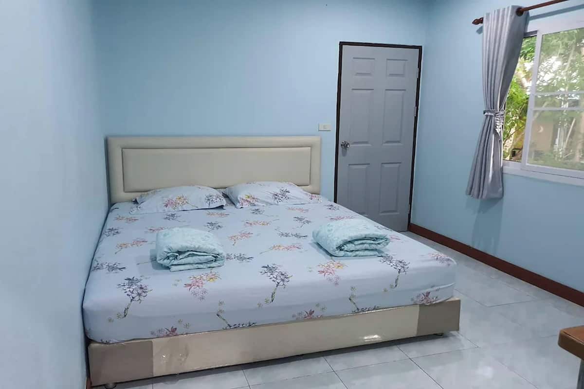 Een bed met bloemenbeddels, een deur en een raam met gordijnen.