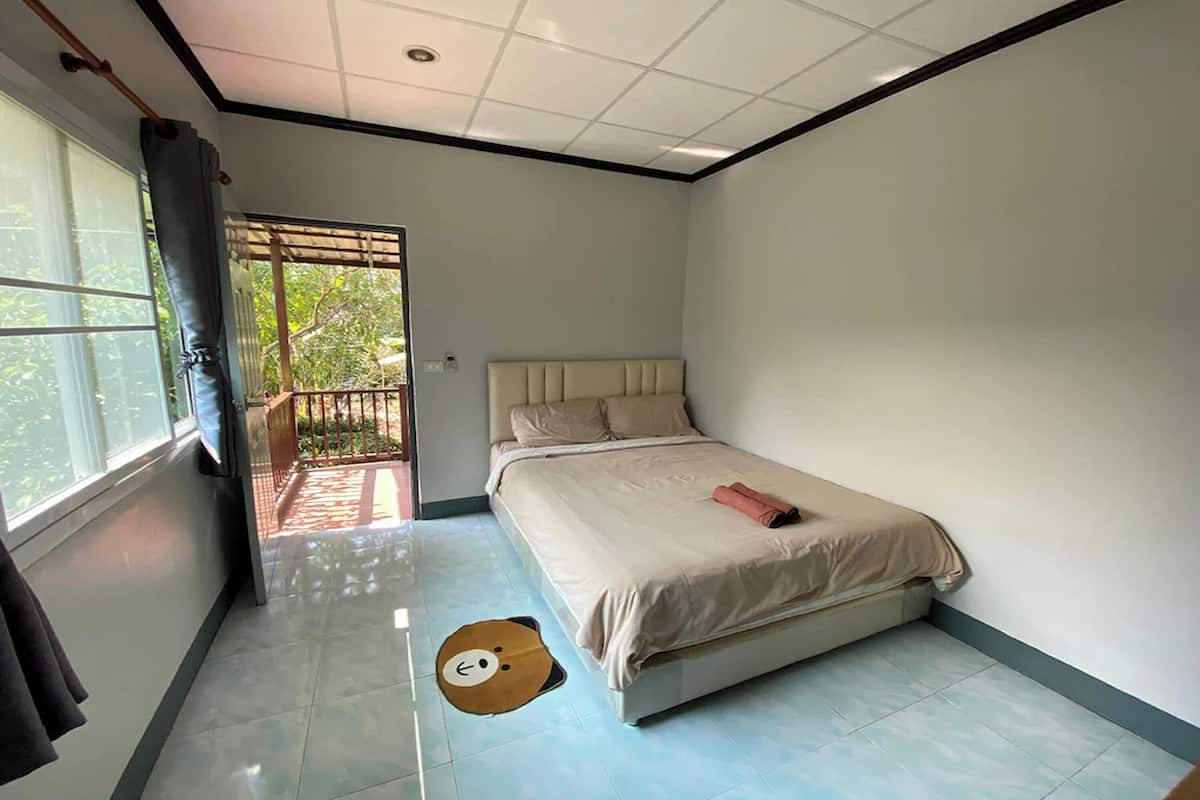 Een slaapkamer met een bed, een raam en een deur naar een buitengebied.