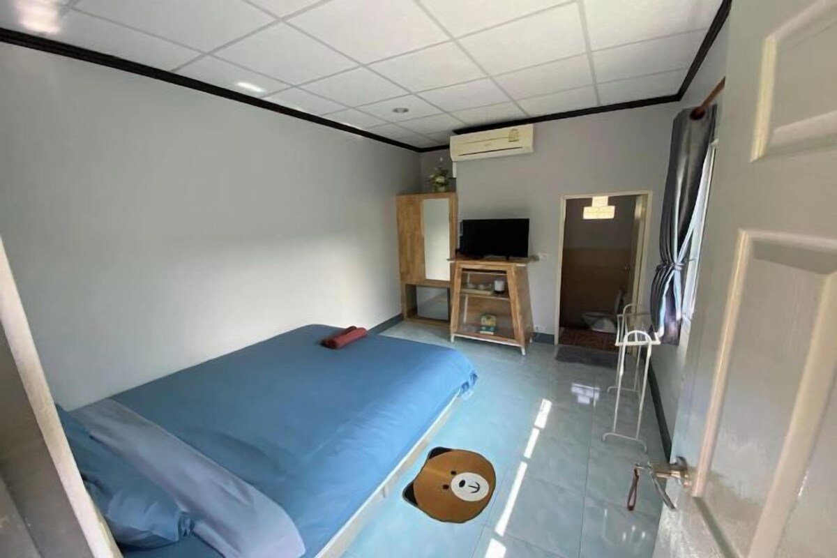 Ein Zimmer mit einem Bett, einem Fernseher, einem Kleiderschrank und einer Tür.
