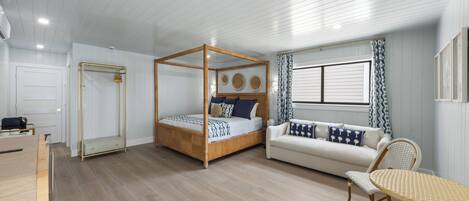 Un dormitorio con cama con dosel, un sofá, una mesa de comedor y un espejo.
