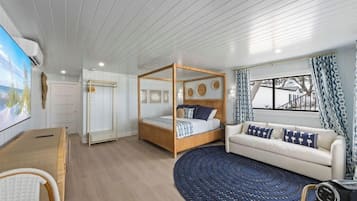 Un dormitorio con cama con dosel, un sofá, una alfombra redonda y un televisor.
