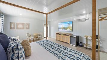 Quarto moderno com uma cama grande, uma TV, uma escrivaninha e uma cadeira.