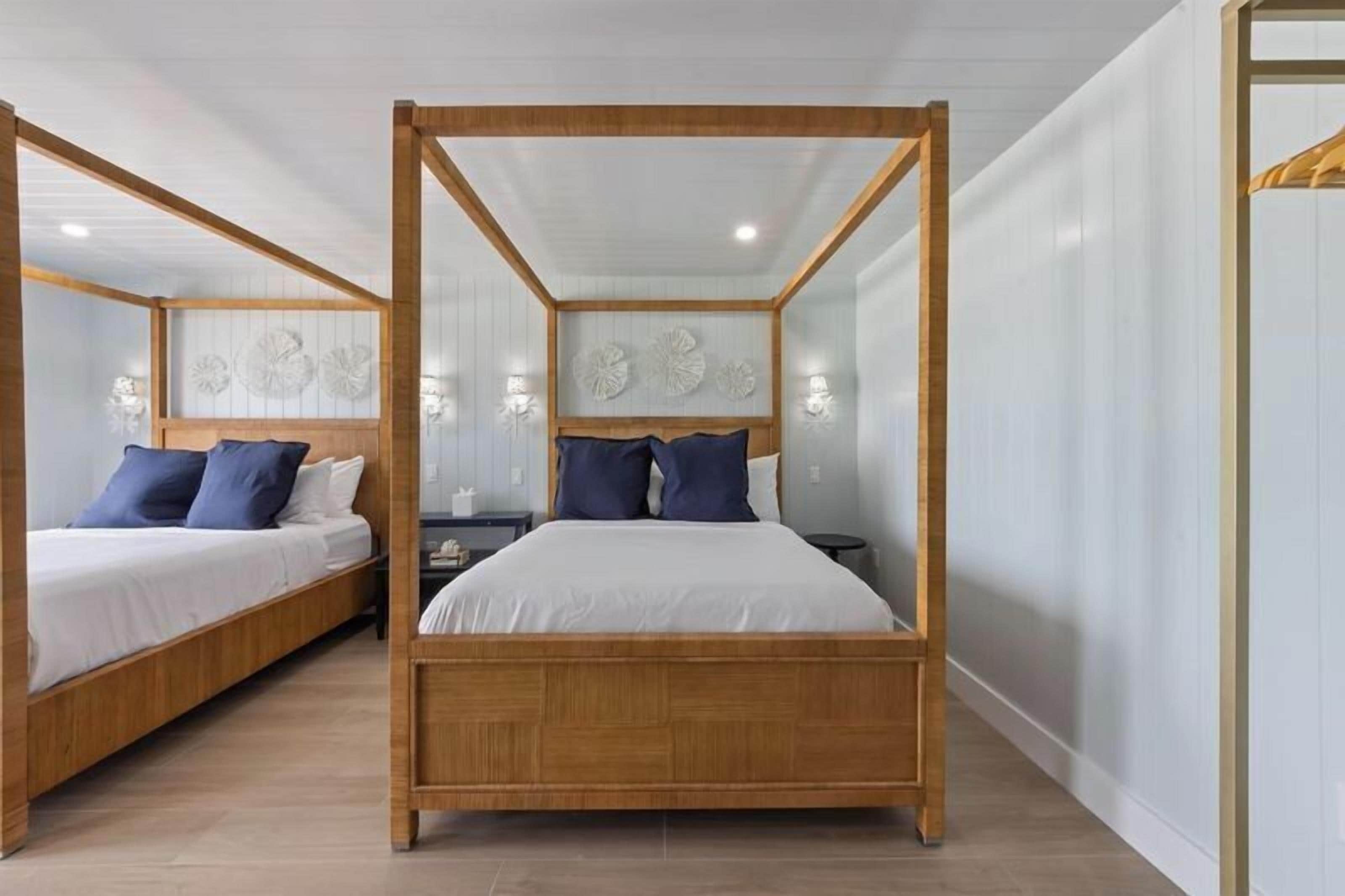A bedroom with two wooden four-poster beds, white bedding, and decorative wall art.