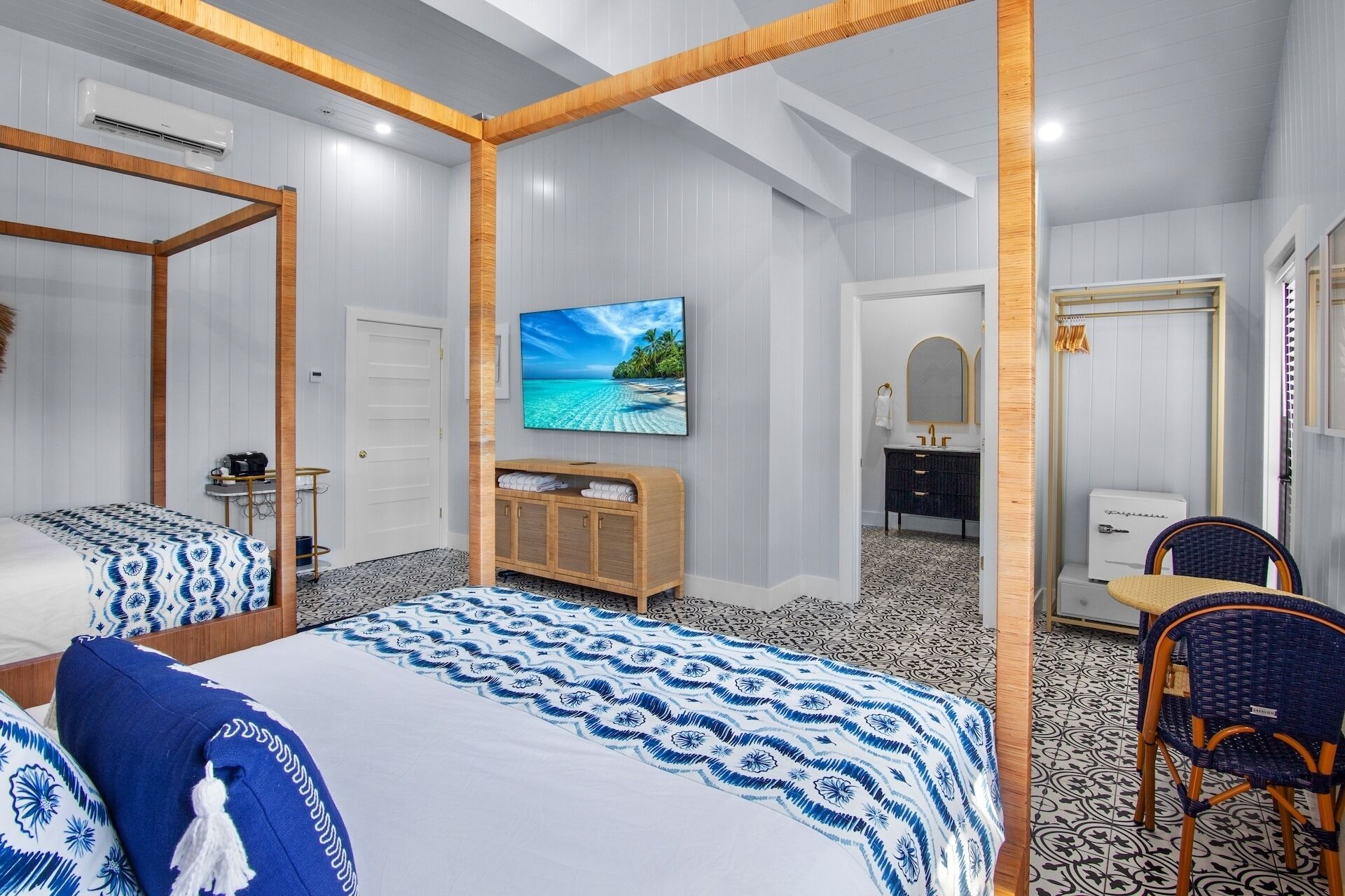 A hotel room with a large bed, a TV, a wooden wardrobe, a bathroom with a mirror, and a chair.