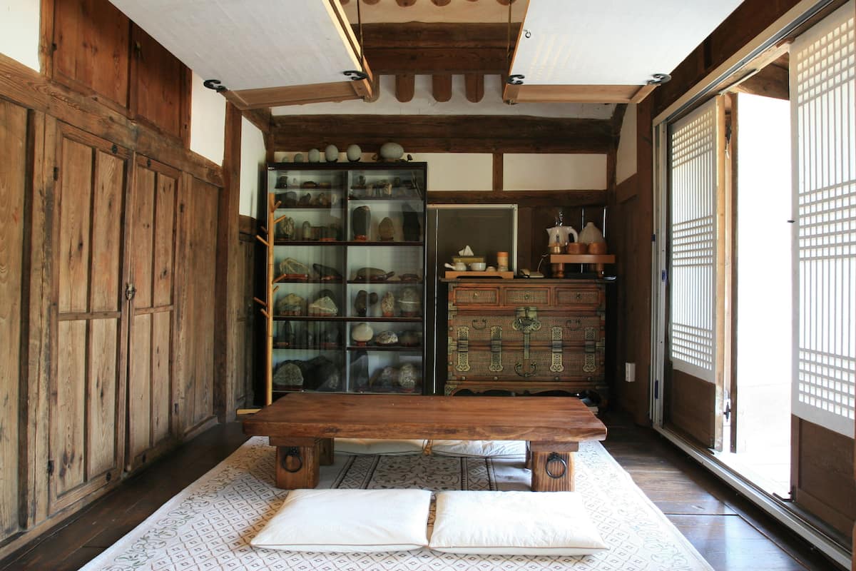 Een traditionele Japanse kamer met tatami vloerbedekking, een houten tafel en een presentatie van keramiek.