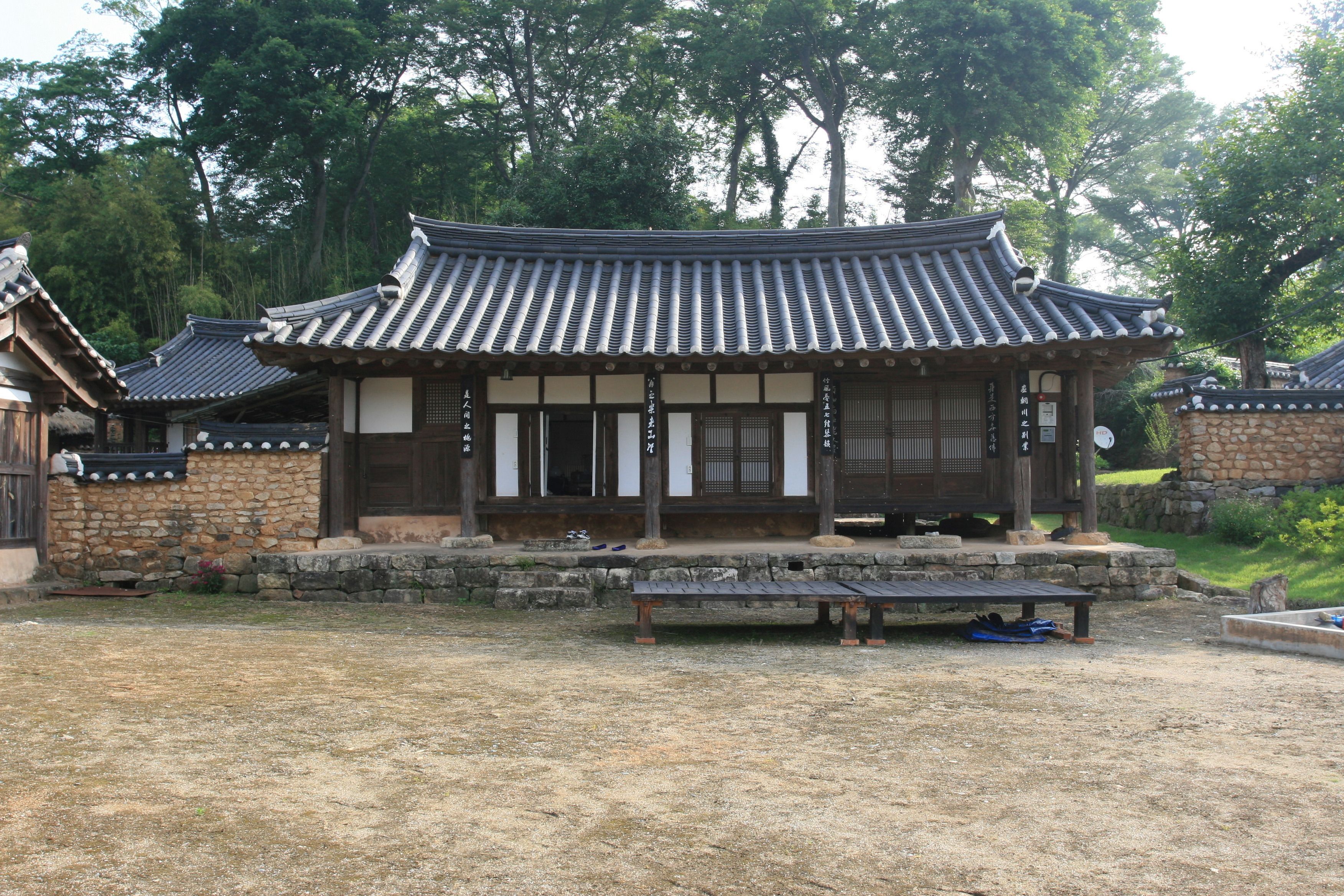 Een traditioneel Koreaans paviljoen met een pannendak, houten balken en stenen muren.