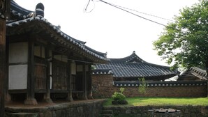 A traditional Korean building with wooden architecture, stone steps, and a courtyard with stone pots. - Yi Jin-rae's Historic House (Boseong)