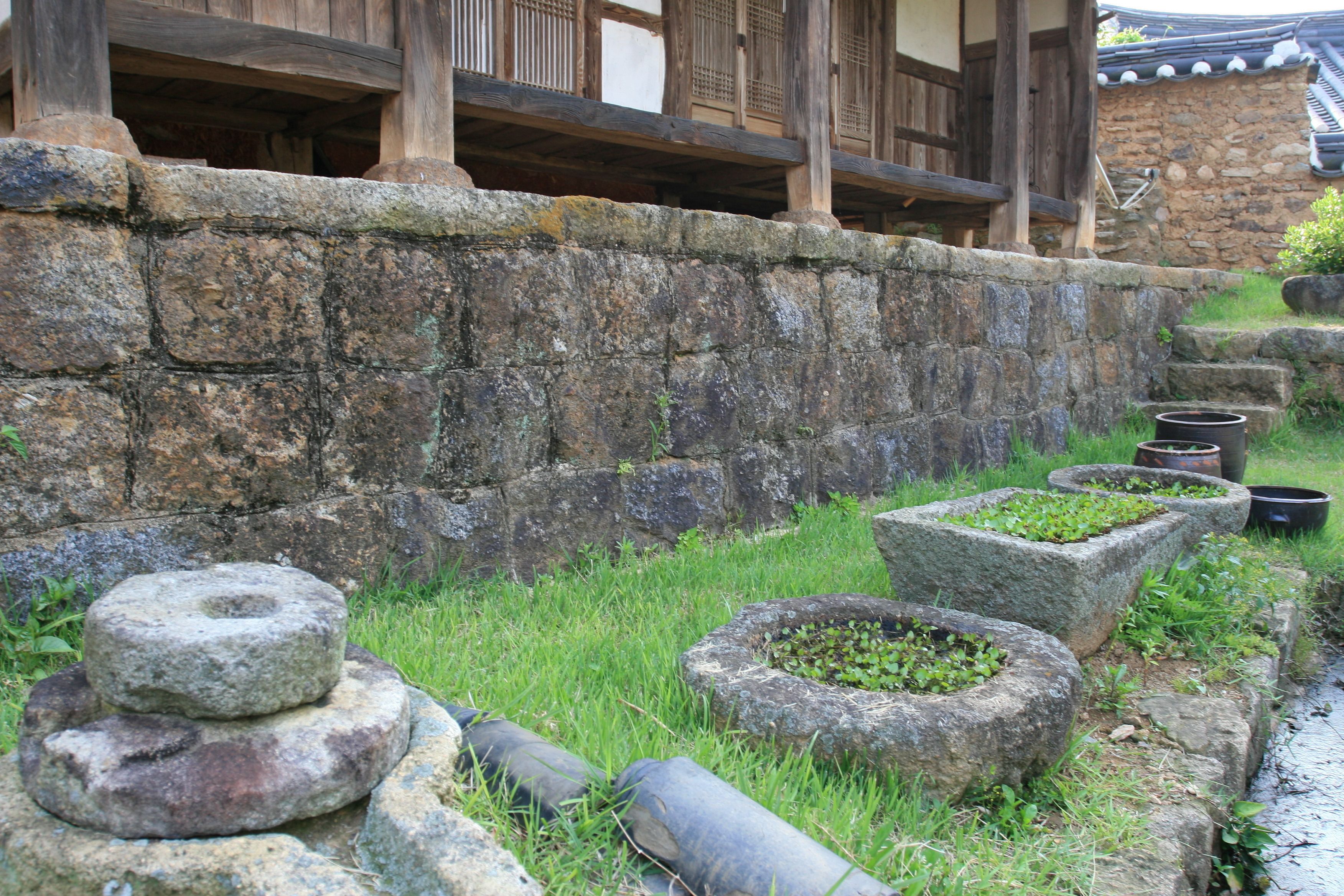 Un muro de piedra tradicional con una escalera de piedra que conduce a un edificio de madera con tejado de tejas.