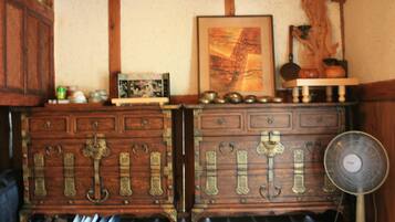 A wooden dresser with ornate metal handles and a fan on the right.