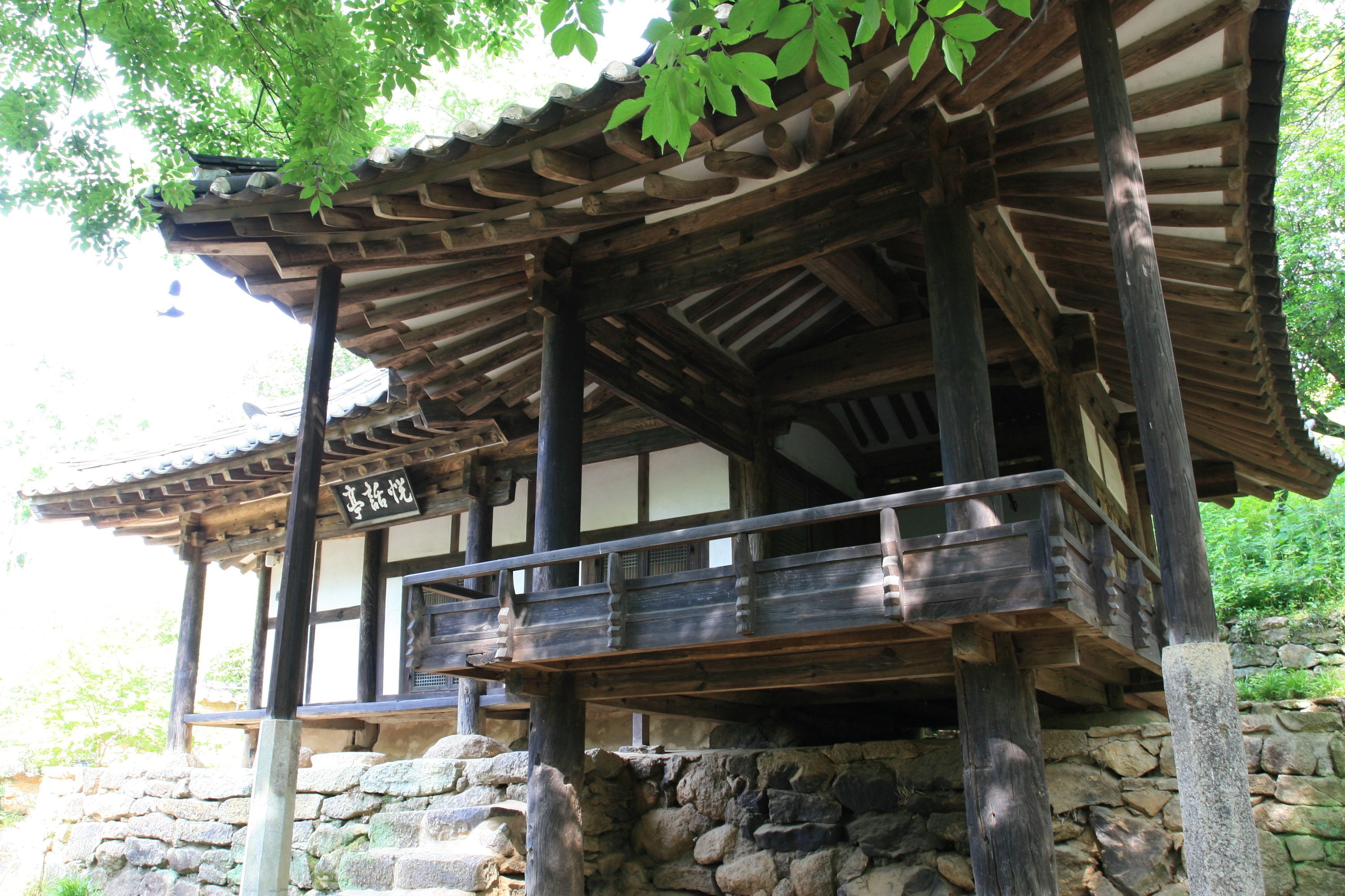 A traditional wooden structure with a stone base, featuring a balcony and a sign.