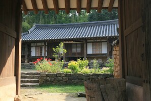 Un bâtiment traditionnel coréen, doté d’un toit en tuiles, d’une structure en bois et d’un mur de pierre orné de plantes.