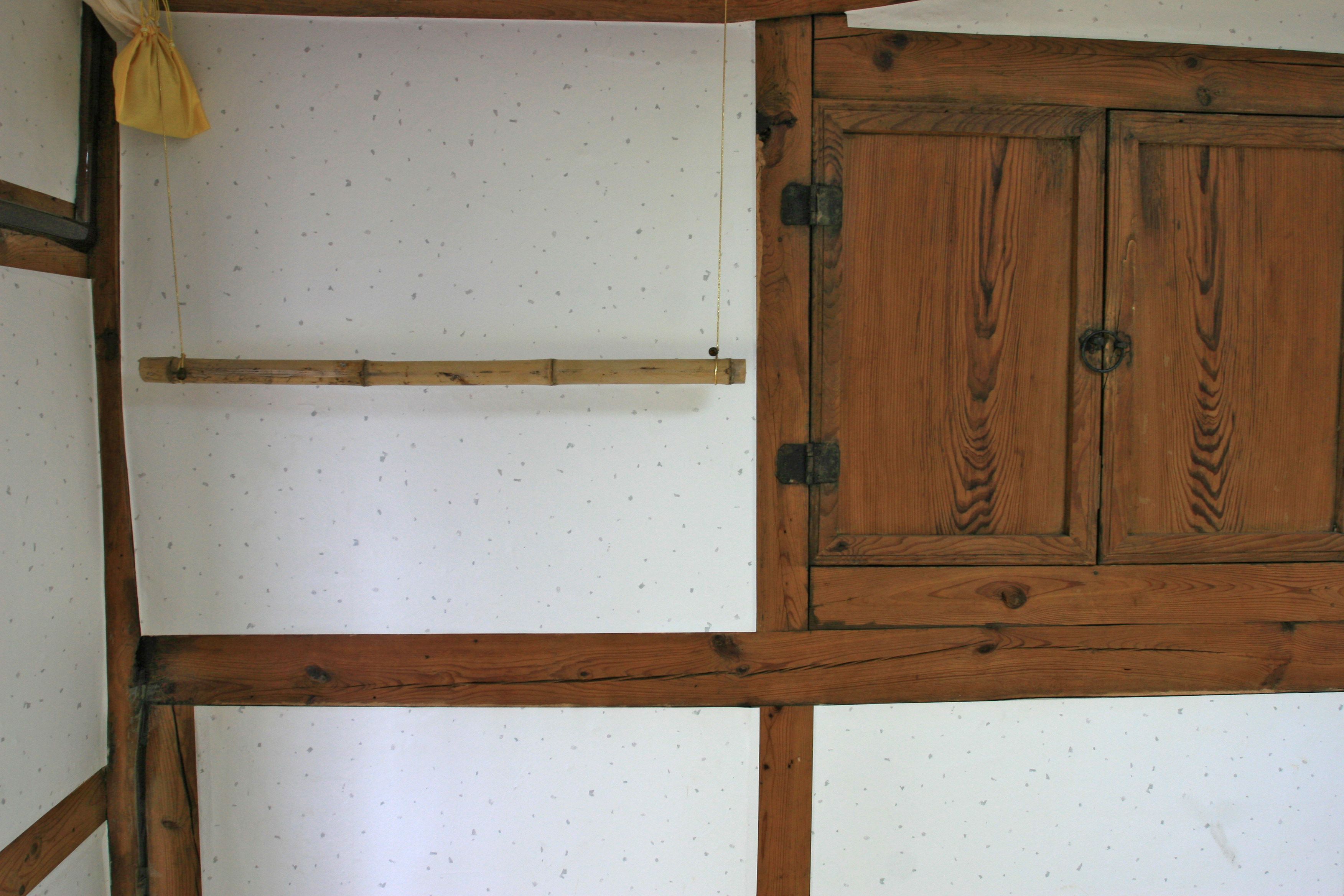 A room with exposed wooden beams, a wooden cabinet, and a hanging yellow cloth.