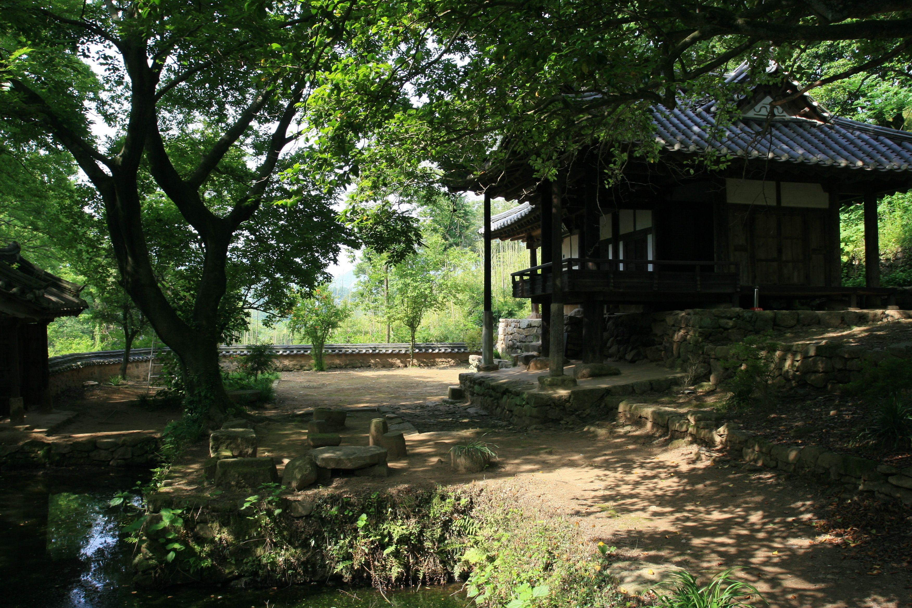 A traditional Japanese building with a wooden structure and a stone pathway leading to a small pond.
