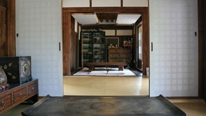 A traditional Japanese room with tatami flooring, a low wooden table, and a bookshelf. - Yi Jin-rae's Historic House (Boseong)