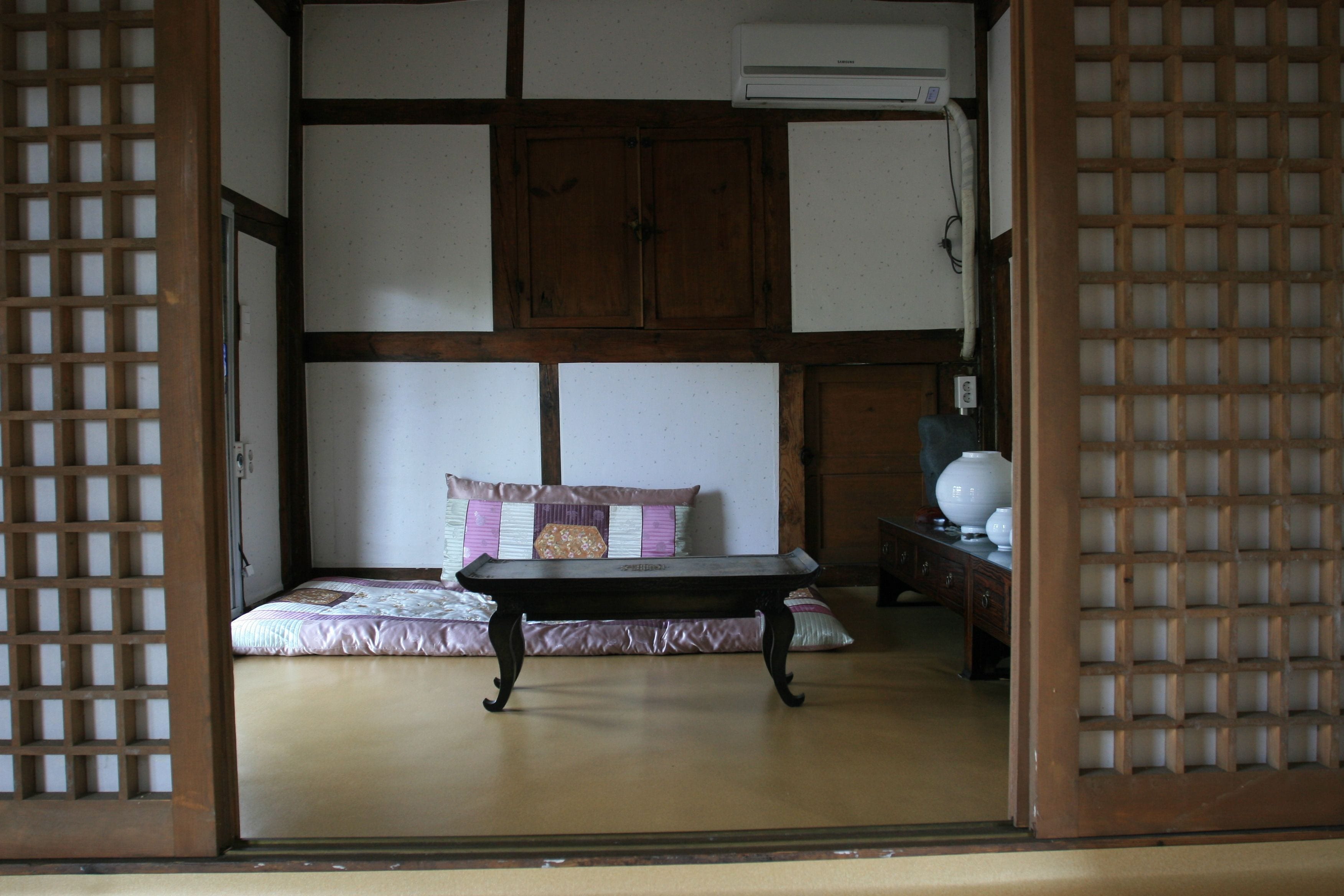 A traditional Japanese room with tatami flooring, a low wooden table, a cushioned bench, and a wooden wardrobe.