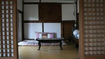 A traditional Japanese room with tatami flooring, a low wooden table, a cushioned bench, and a wooden wardrobe.
