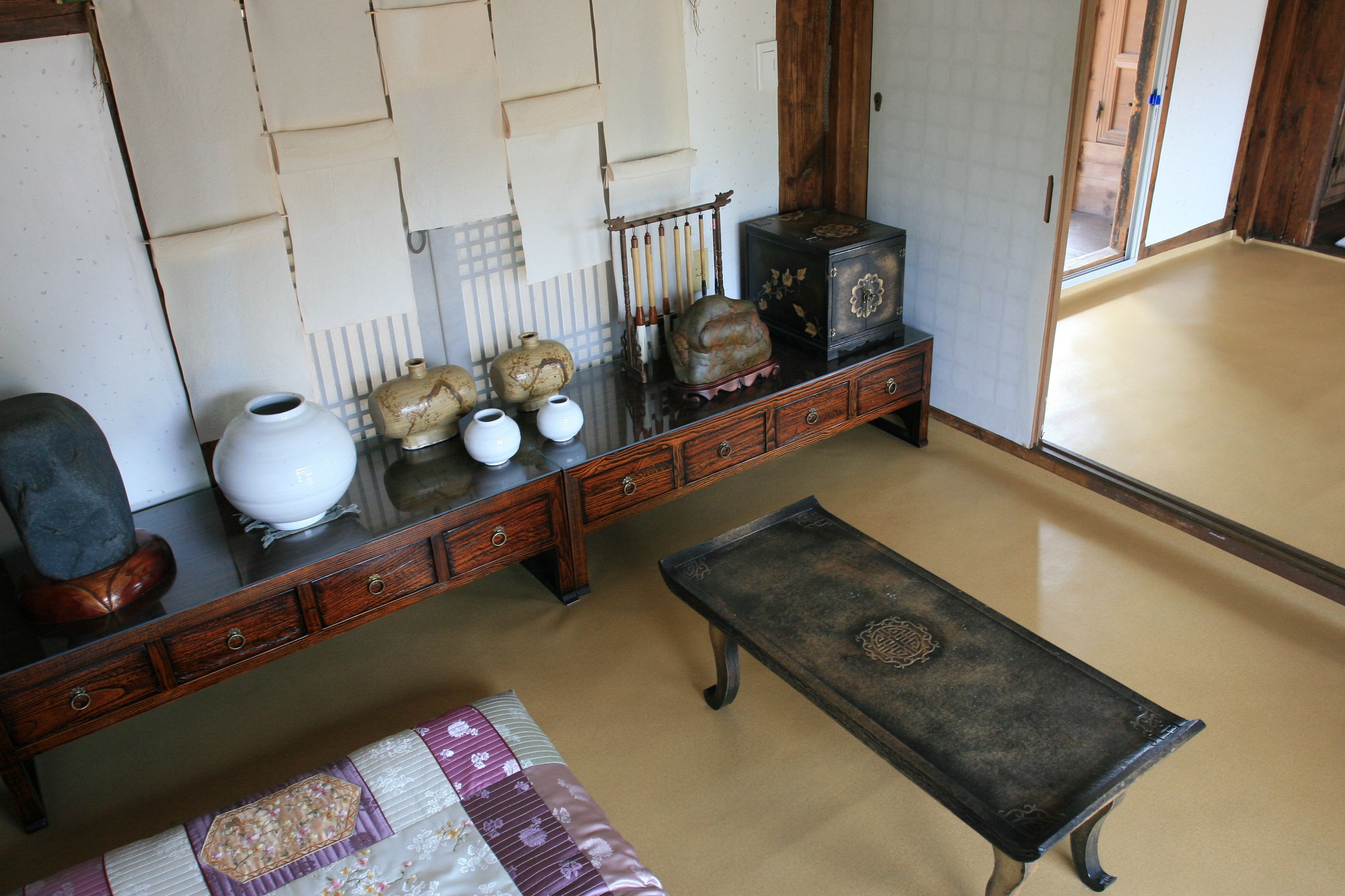 A traditional room with a wooden bench, a low table, and a cabinet with decorative items.