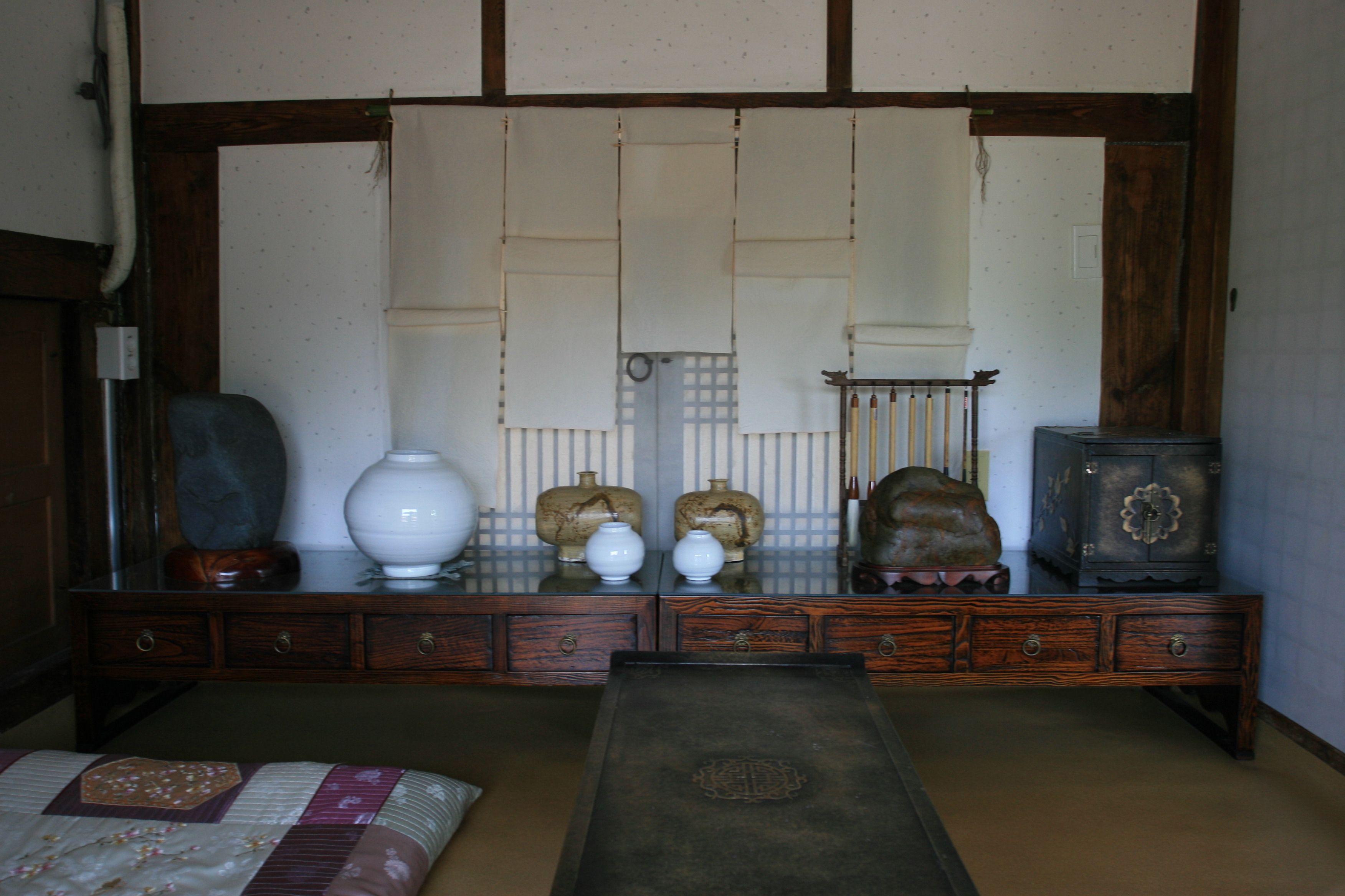 A traditional Japanese room with tatami flooring, a low wooden table, and a large mirror with a wooden frame.