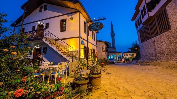 A traditional building with a staircase leading to a balcony, surrounded by potted plants and flowers. - Akcasu Konuk Evi (Safranbolu)