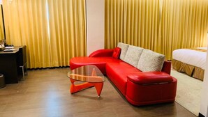 Une chambre d’hôtel moderne avec un canapé rouge, une table basse en verre et un lit.