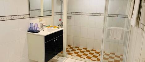 A bathroom with a shower, a sink with toiletries, and a toilet.