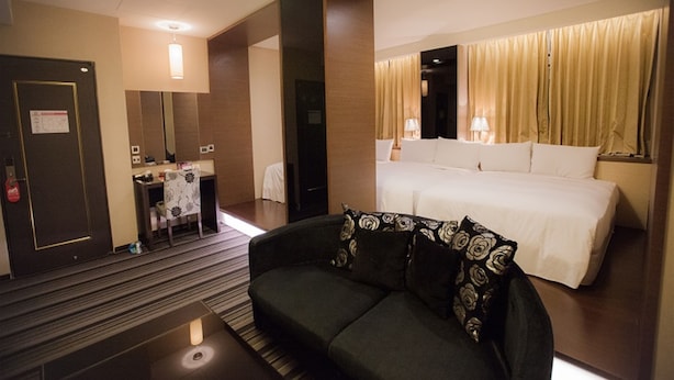 Une chambre d’hôtel avec un lit, un canapé, un bureau et un miroir.