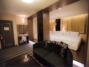 A hotel room with a bed, a sofa, a desk, and a mirror. - Kai Shen Sinsu Hotel (Taitung)